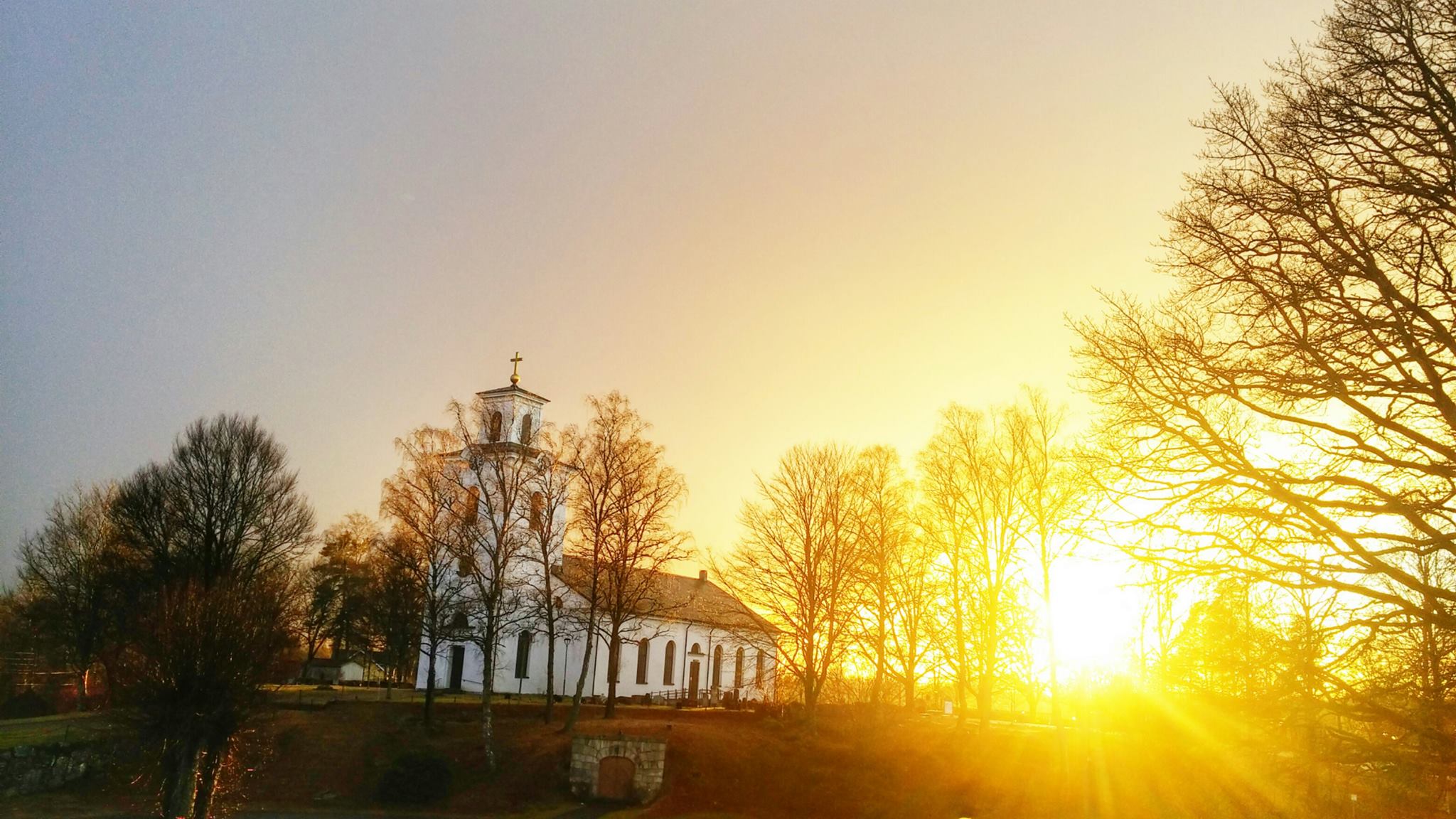 Exteriörbild på Öja kyrka i solnedgång.