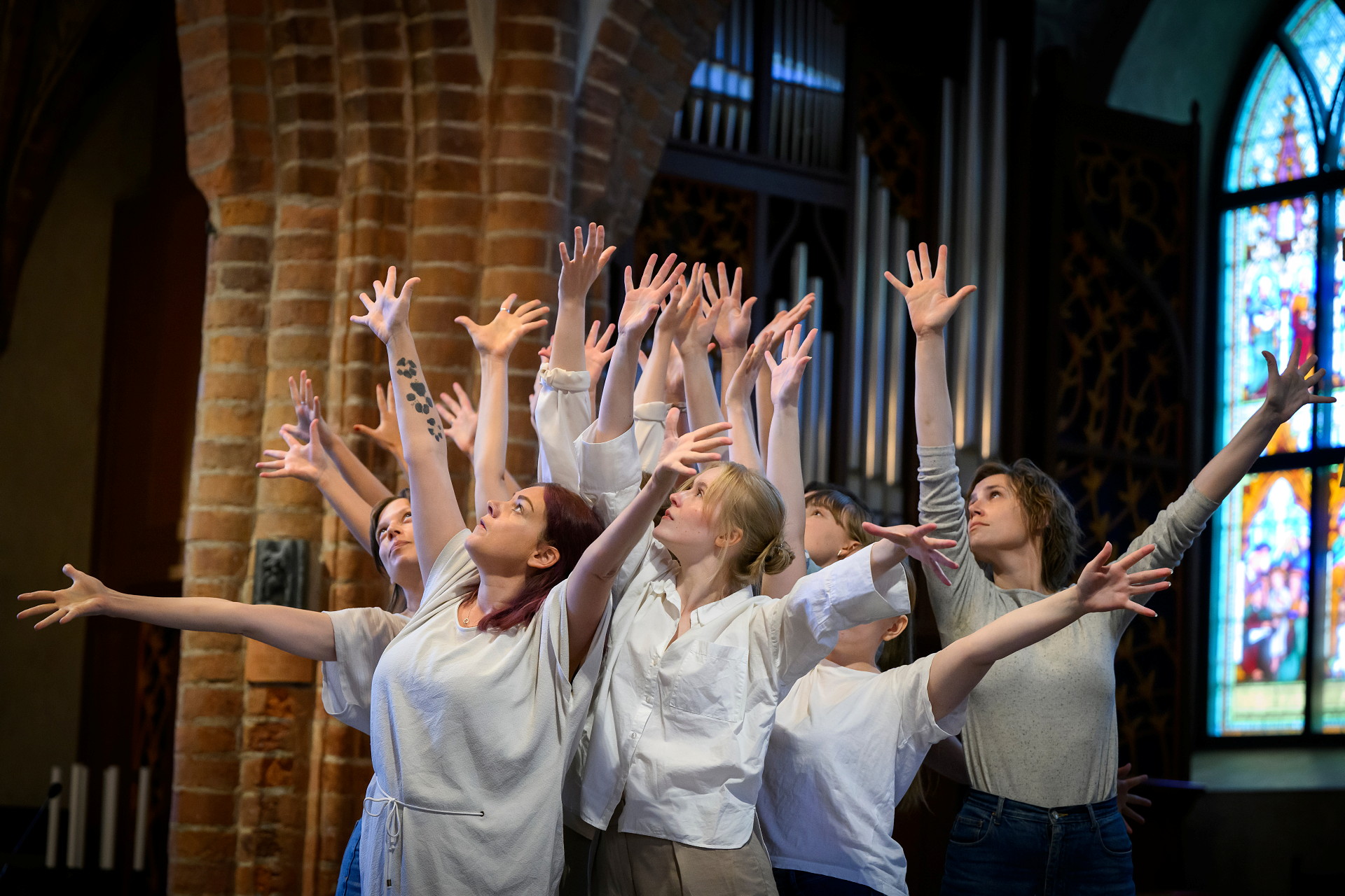 En grupp kvinnor står i en kyrka med armarna uppsträckta.