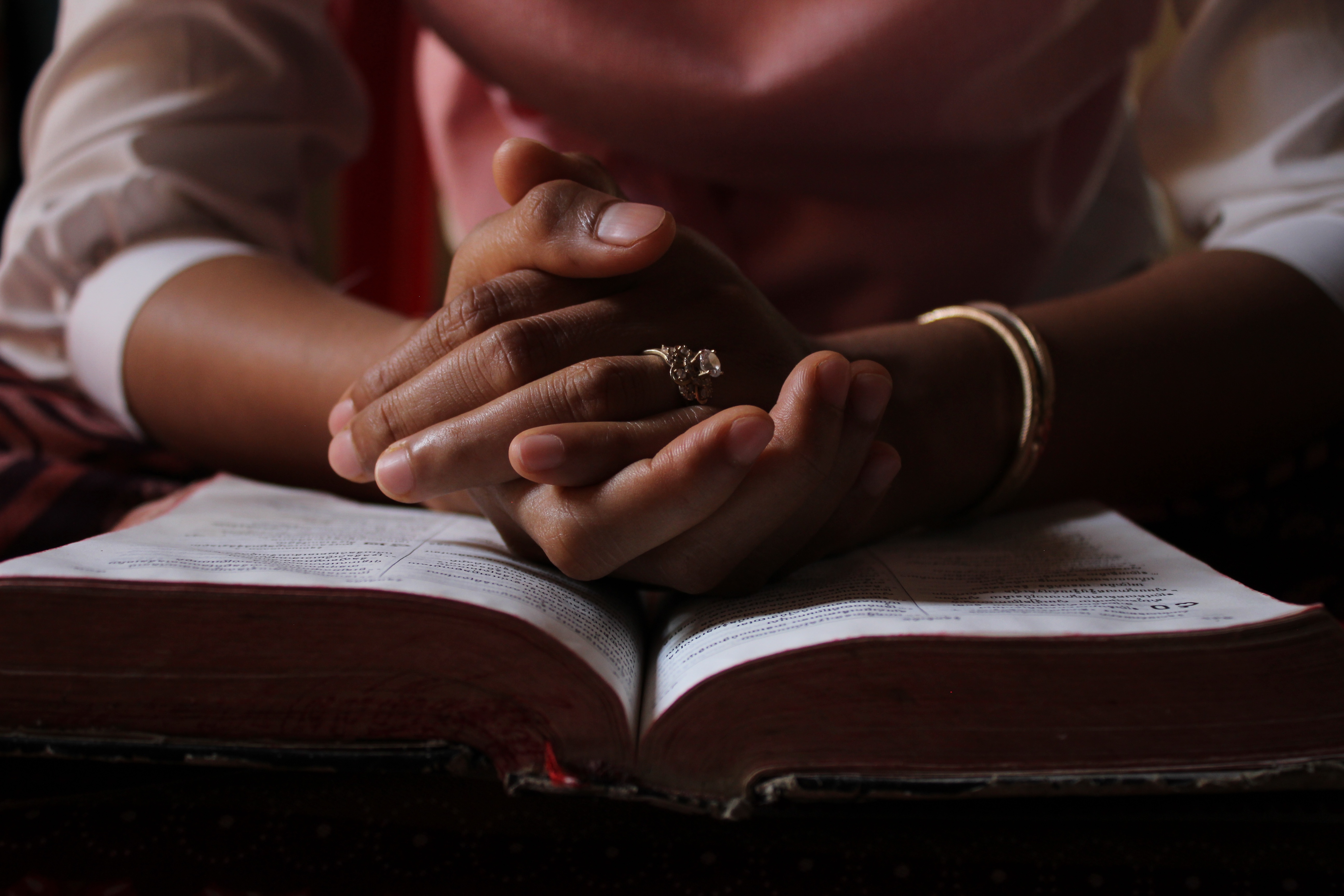 Händer som vilar på en uppslagen bibel.
