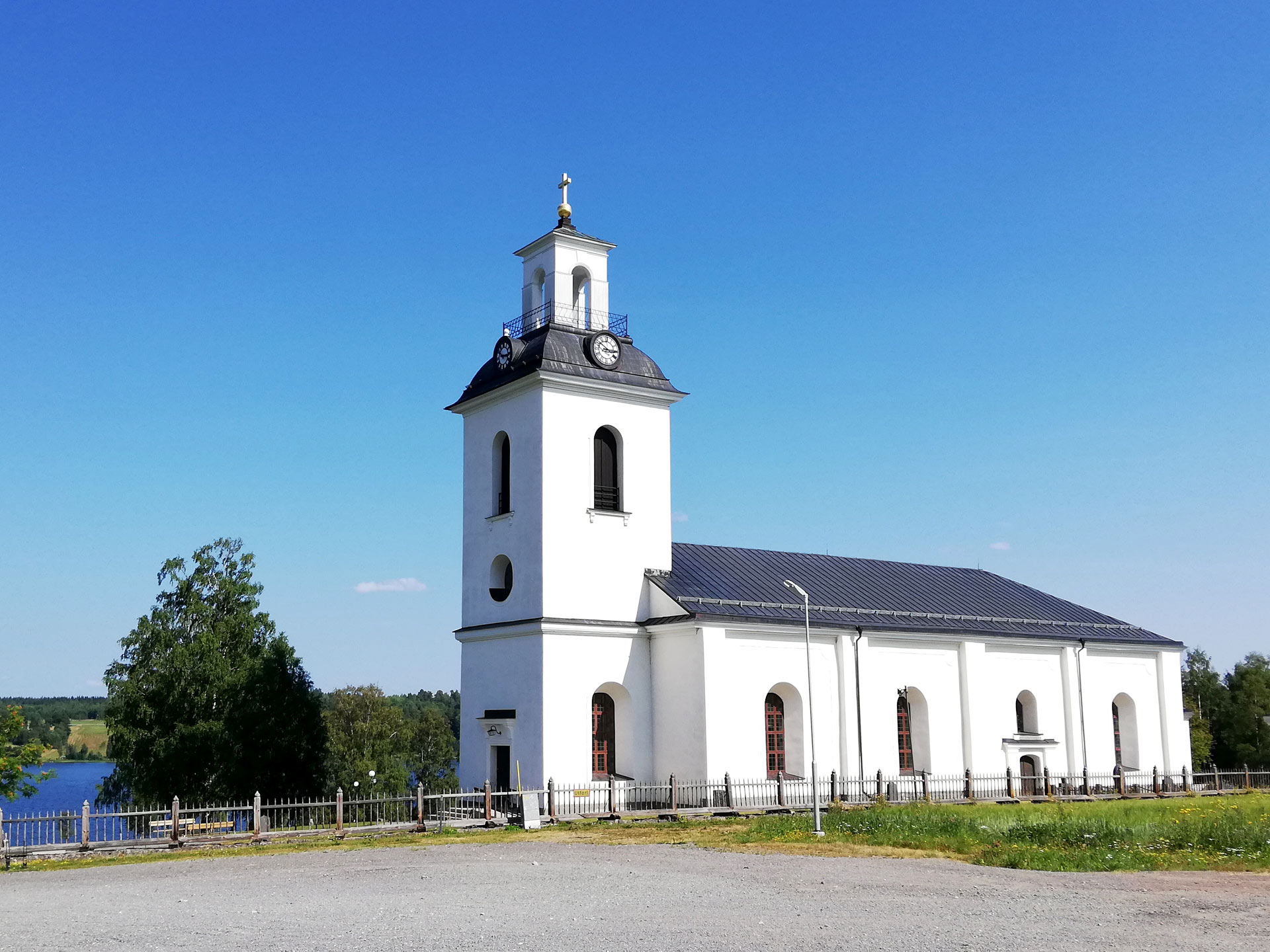 Helgums kyrka. En sommarbild. I bakgrunden skymtar Helgumssjön.