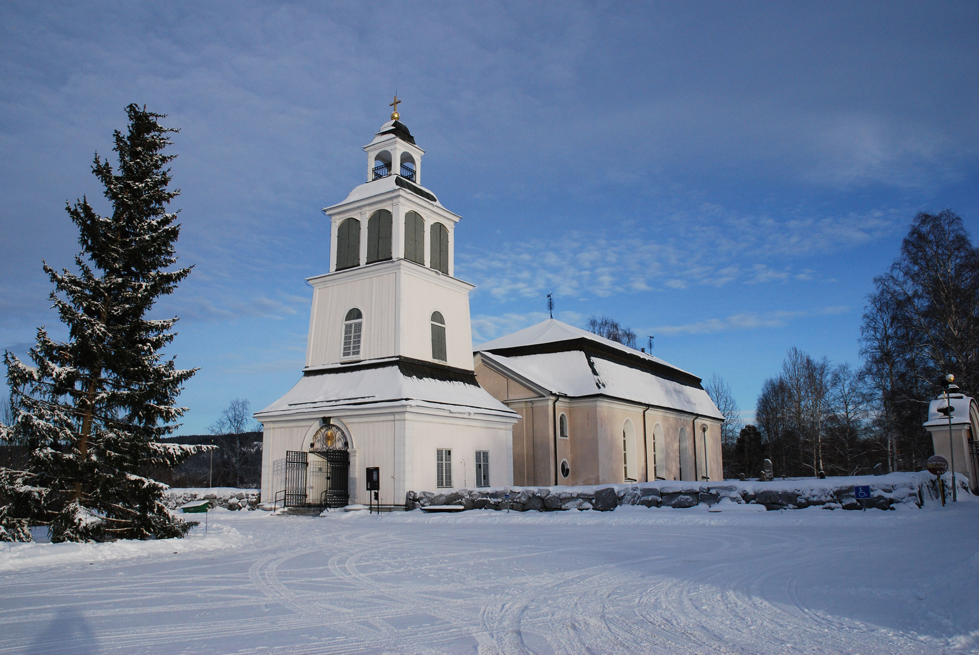 Sollefteå kyrka. En vinterbild. Till vänster står en stor gran.