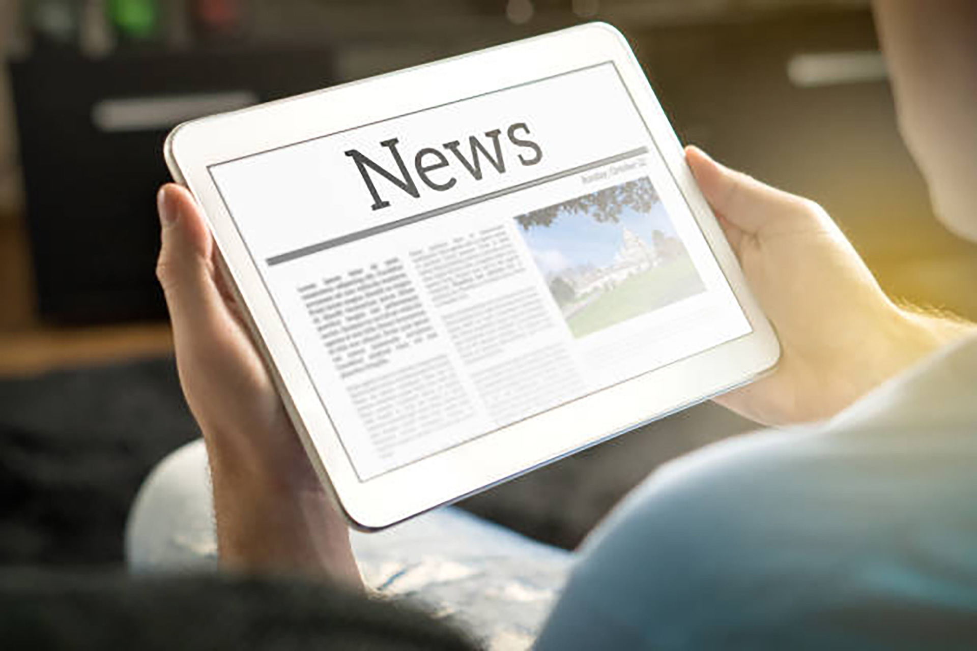 Händer som häller i en läsplatta med texten "News" på
