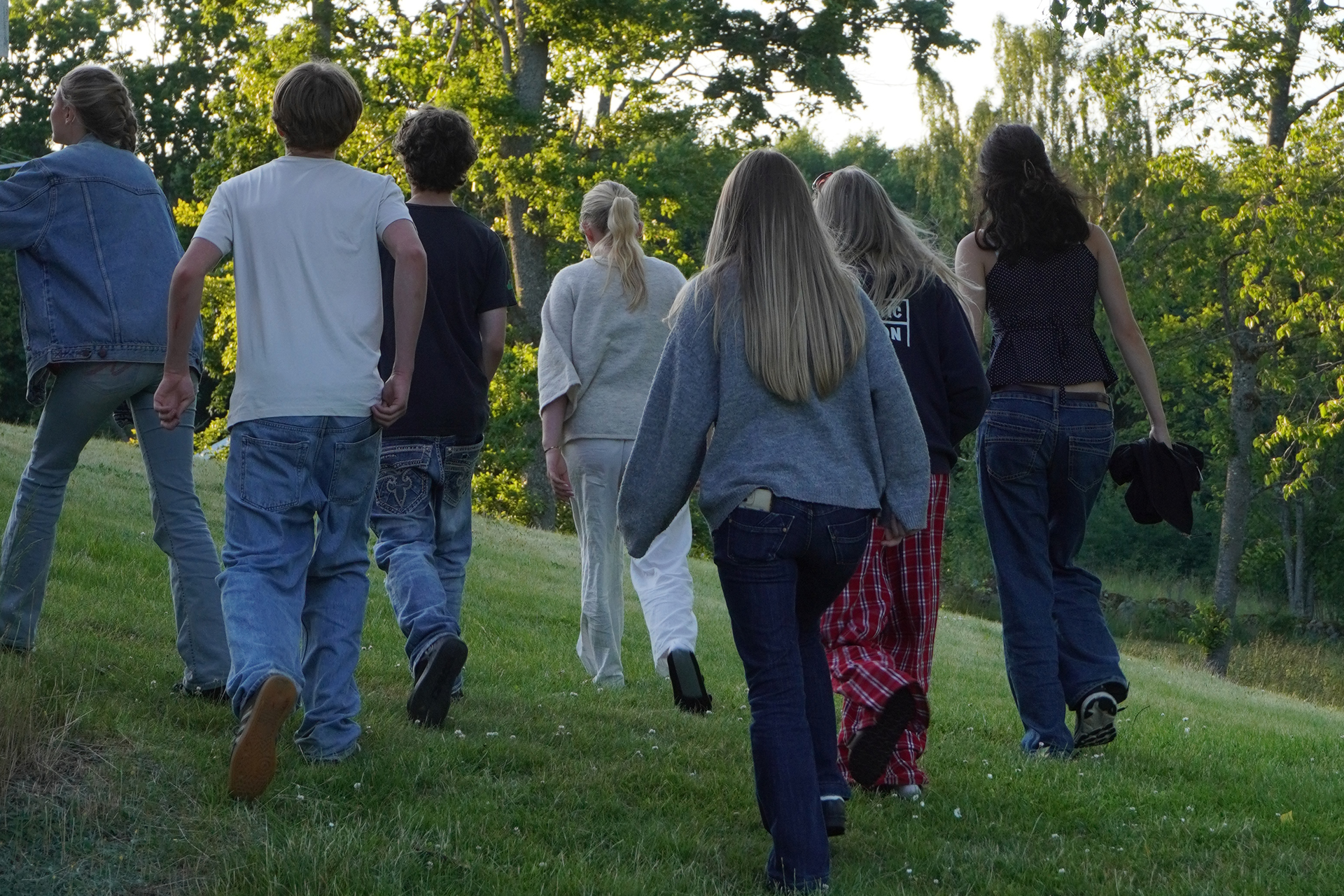 En grupp ungdomar går runt knuten på ett rött hus. 