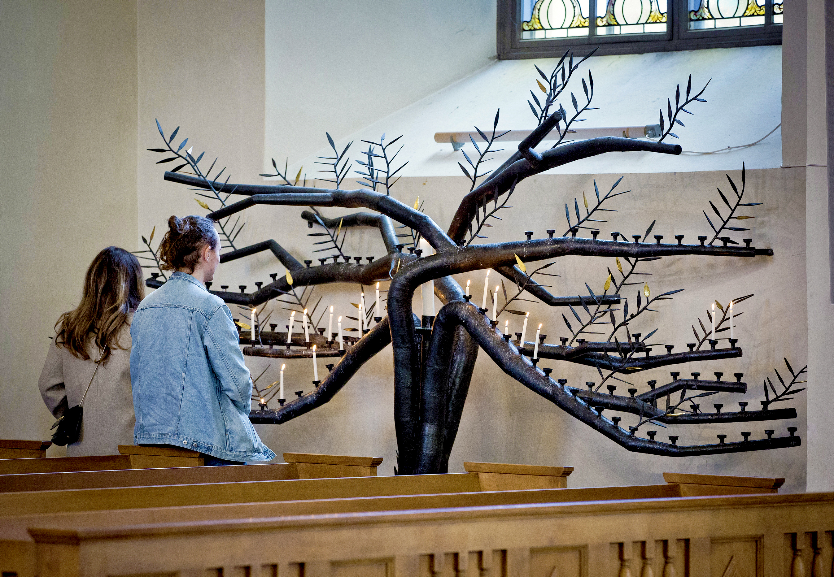 Två personer står vid Domkyrkan i Karlstads ljusträd och tittar på ljusen. 