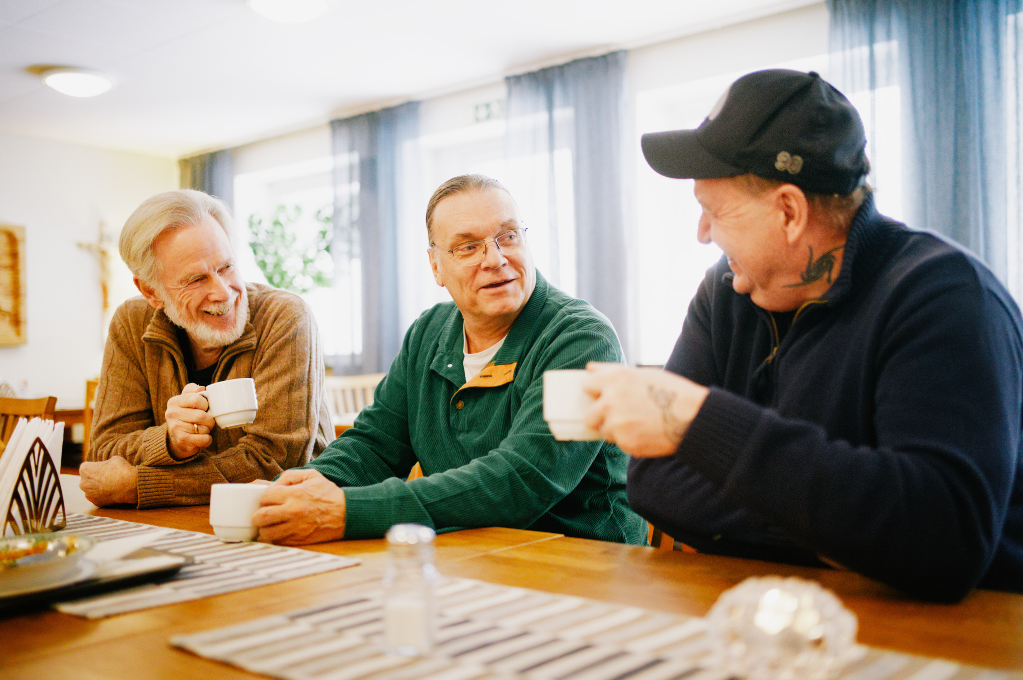 Tre män dricker kaffe vid ett bord