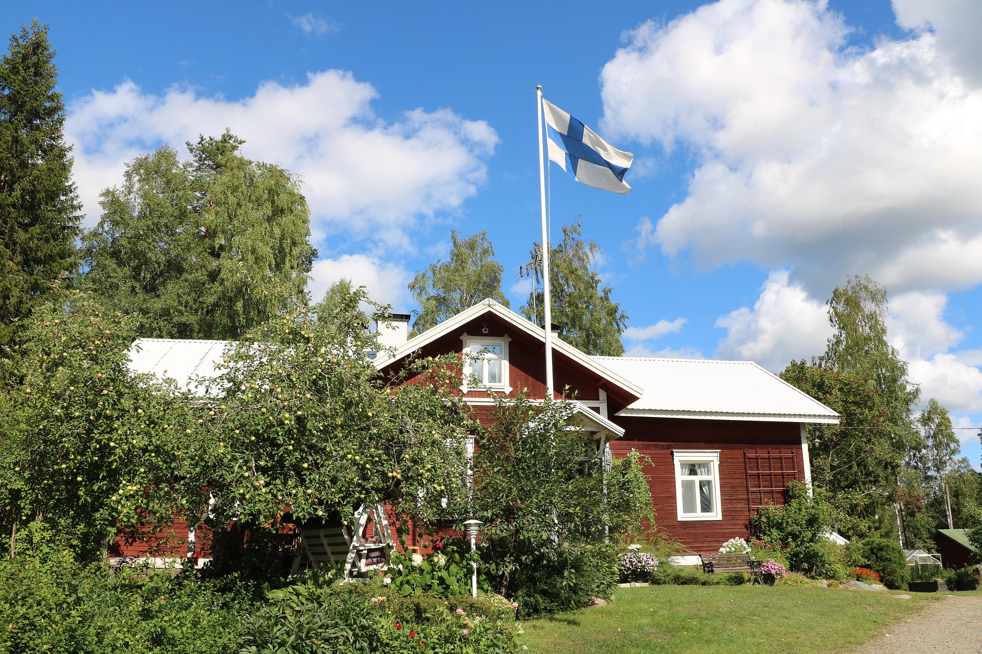 Ett rött hus med finsk flagga och blå himmel