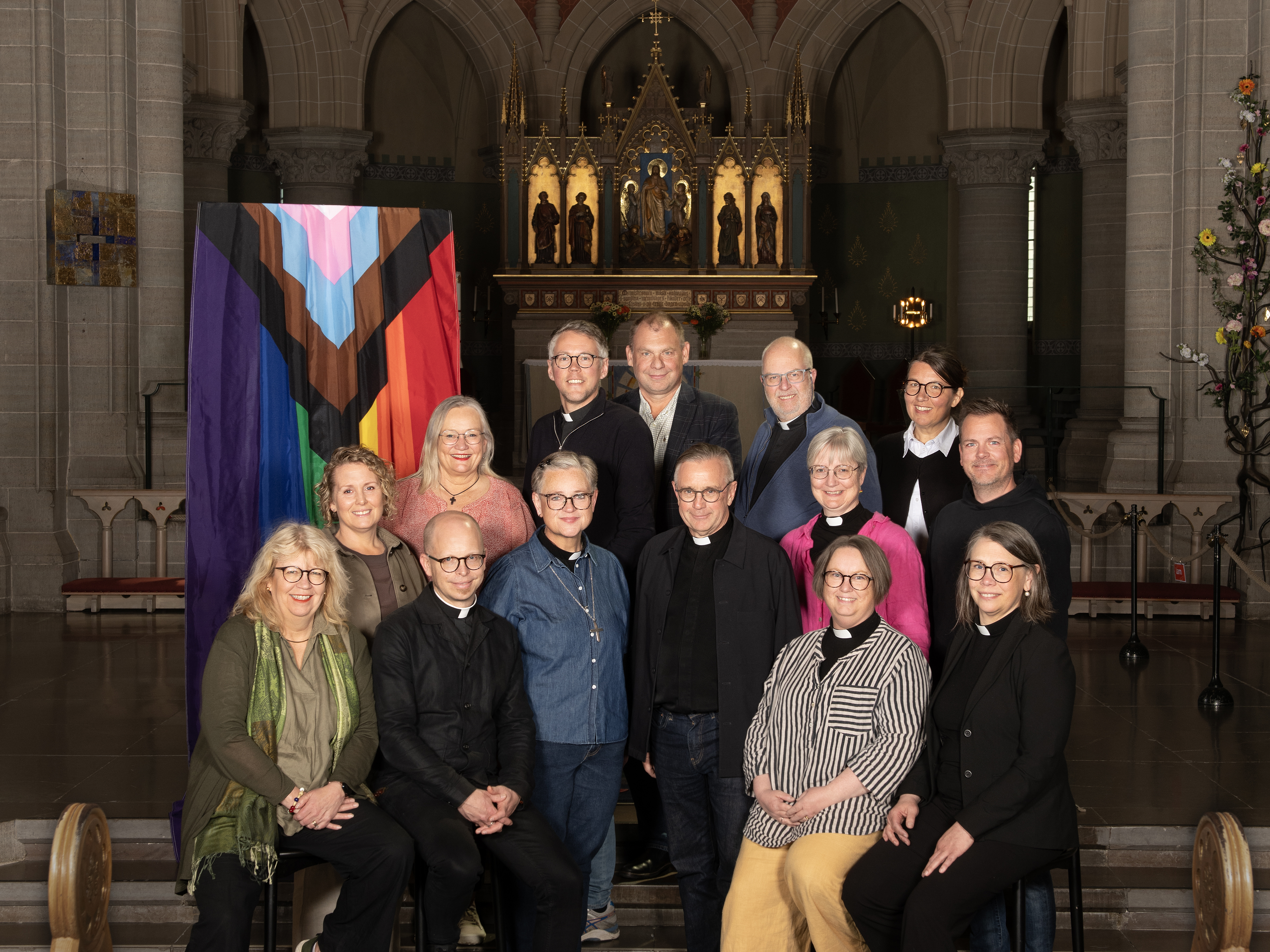 Kvinnor och män samlade vid regnbågsflaggan i Olaus Petri kyrka i Örebro.