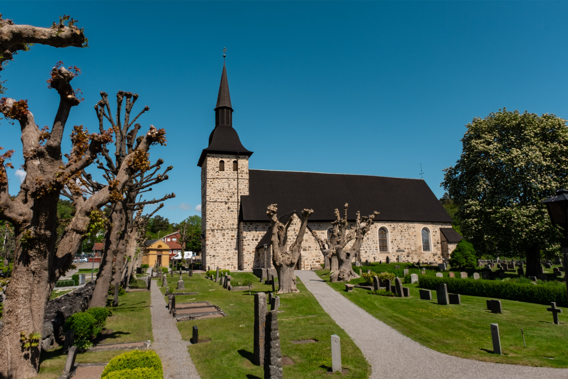 Exteriörbild av Botkyrka kyrka, en murad stenkyrka med svarttjärat tak.