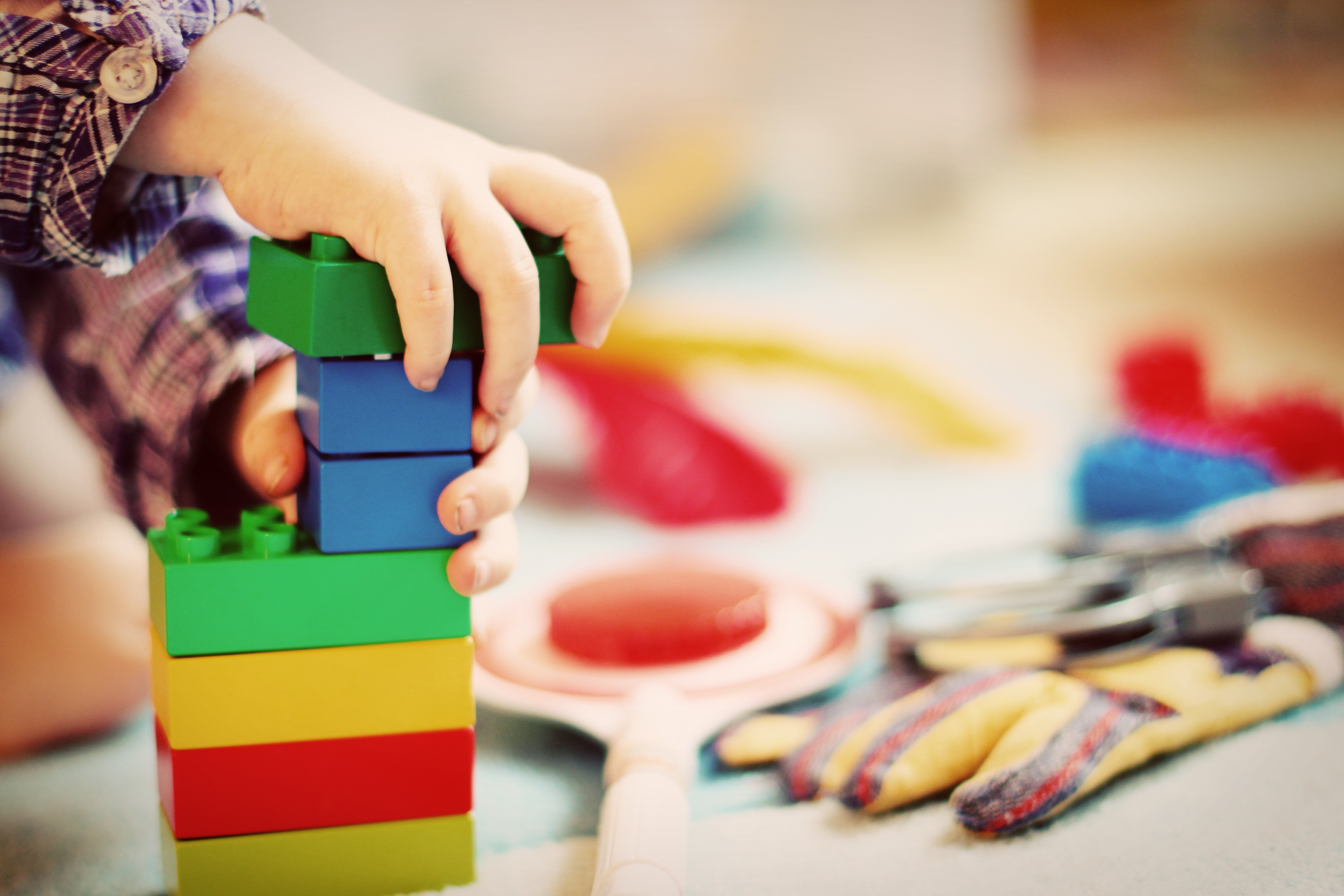 Närbild på småbarnshänder som bygger ett torn med duplo.