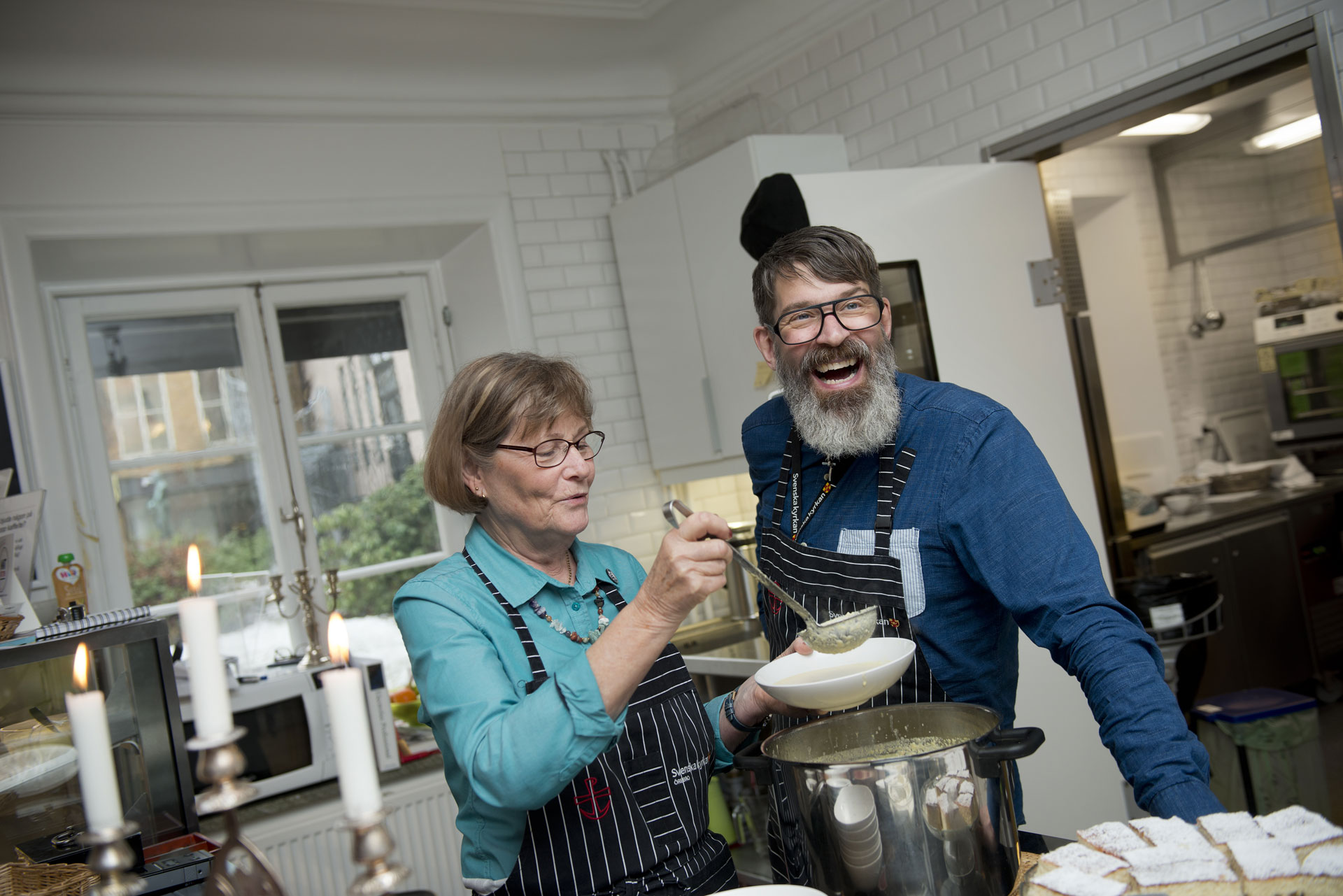 Bilden visar en glad husvärd/husmor Sonny Larsson i samspråk med en ideell medarbetare i Café Nikolai. 