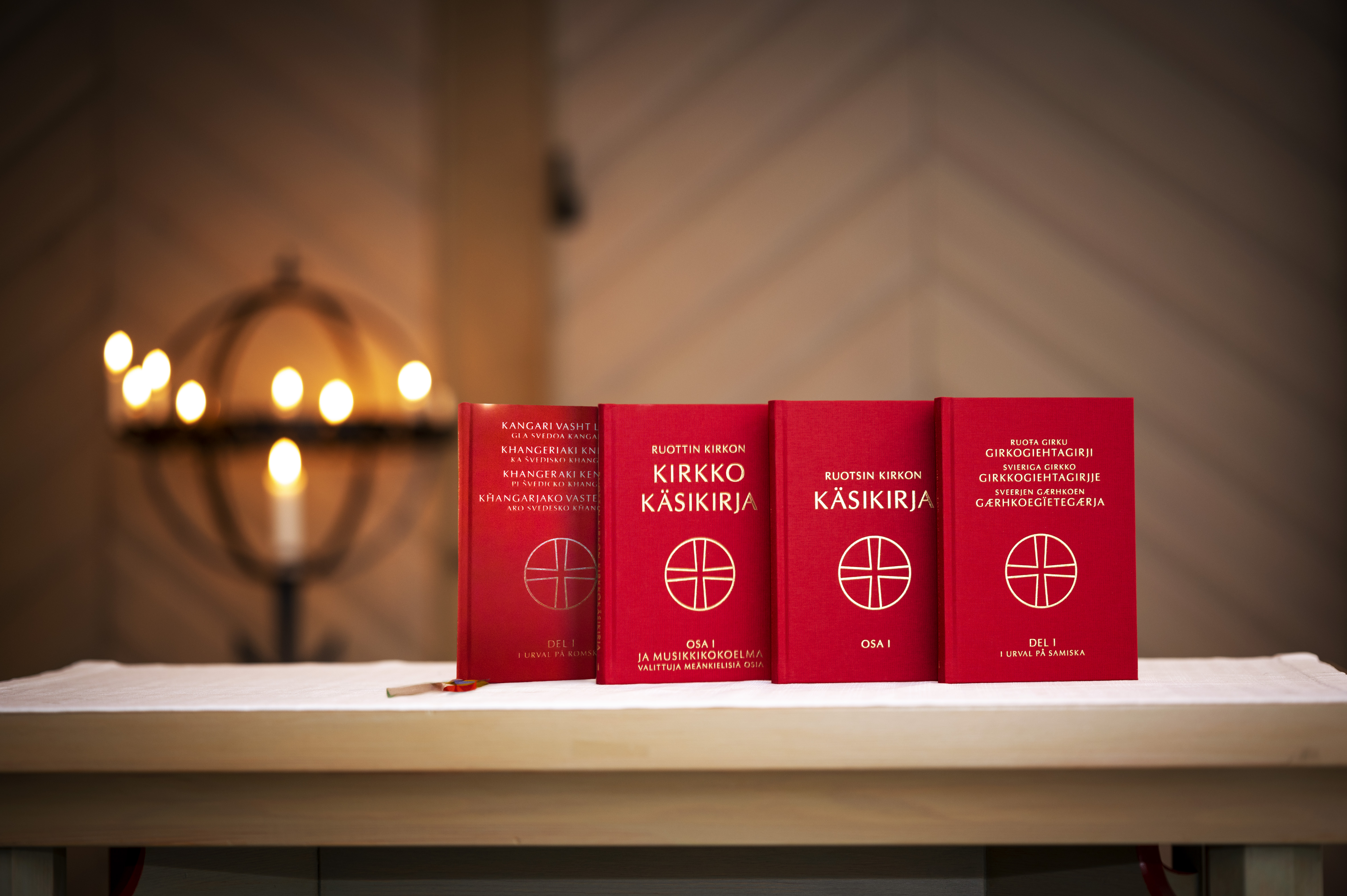 Kyrkohandboken på fyra olika minoritetsspråk står uppställda på ett bord i en kyrka.