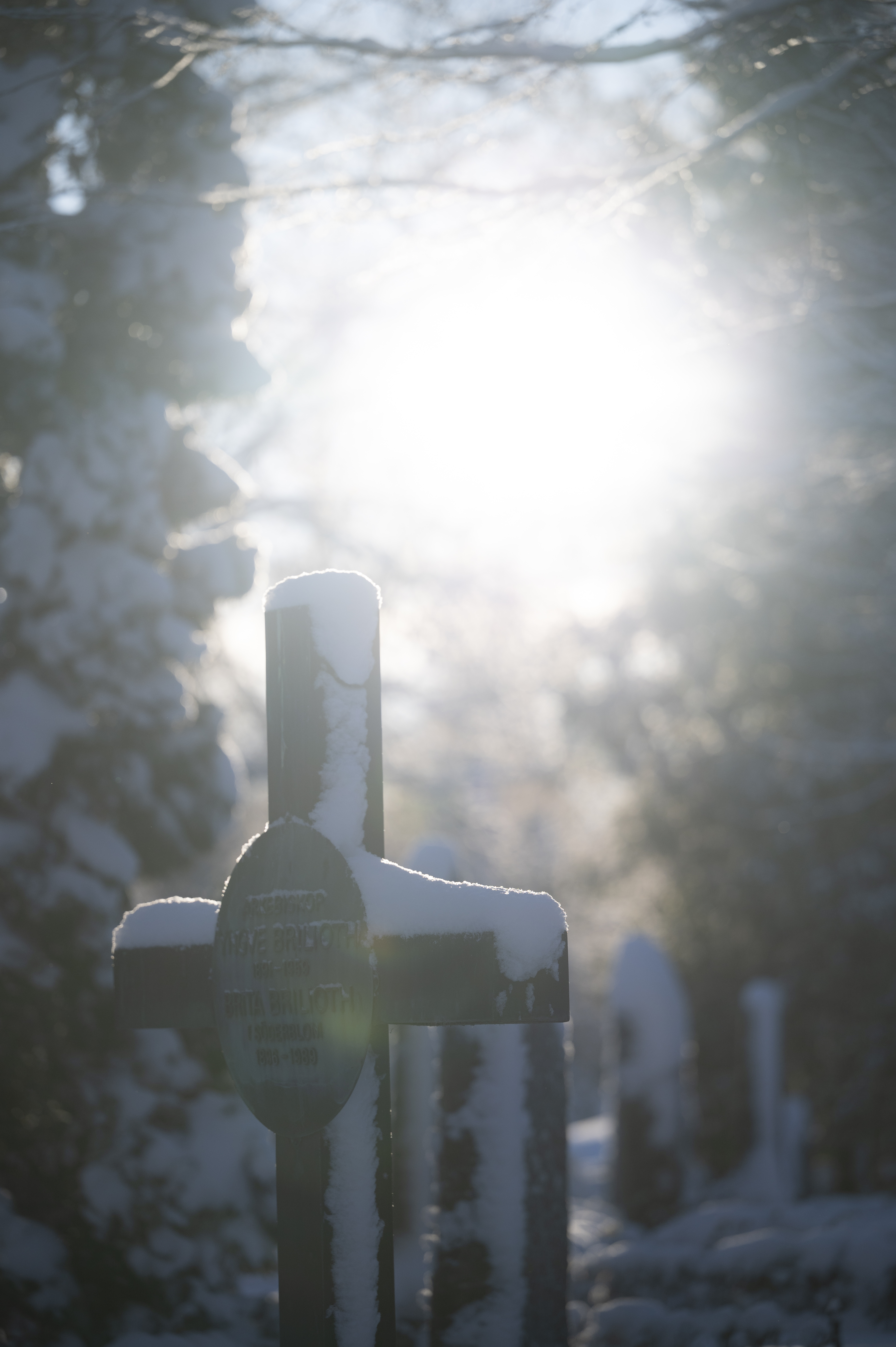 Snö ligger på en gravsten. Solen lyser.