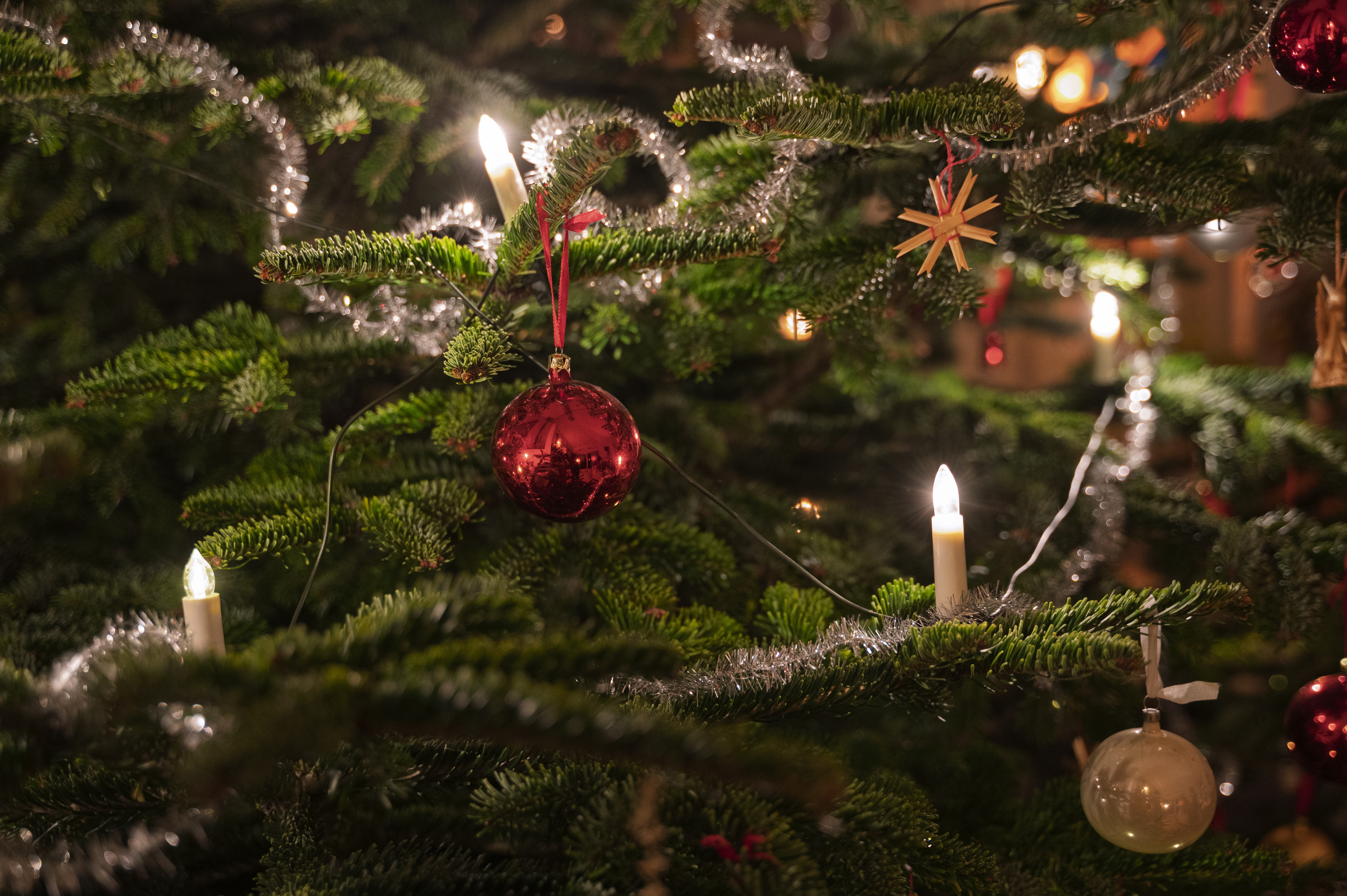 Närbild på en julgran dekorerad med julkulor, glitter och julgransbelysning.