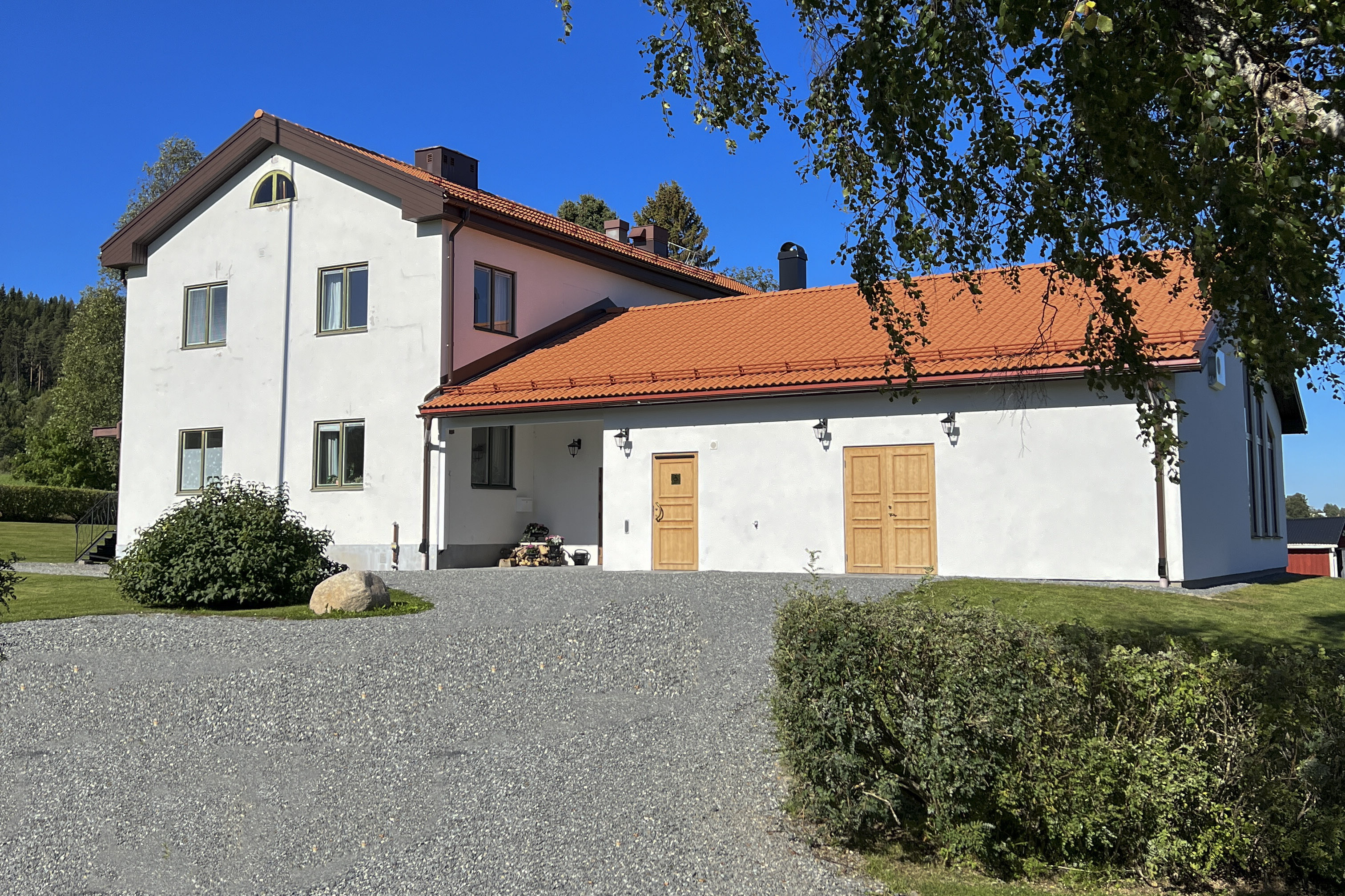 Gaveln på ett vitputsat tvåvåningshus med en lägre utbyggnad. 